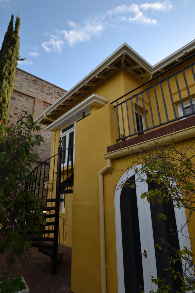 Esempio della facciata di una casa gialla mediterranea a due piani