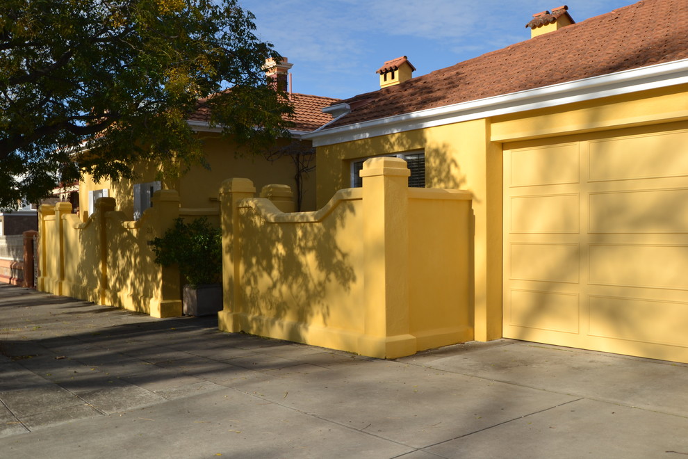 На фото: желтый дом в средиземноморском стиле с облицовкой из цементной штукатурки и двускатной крышей с