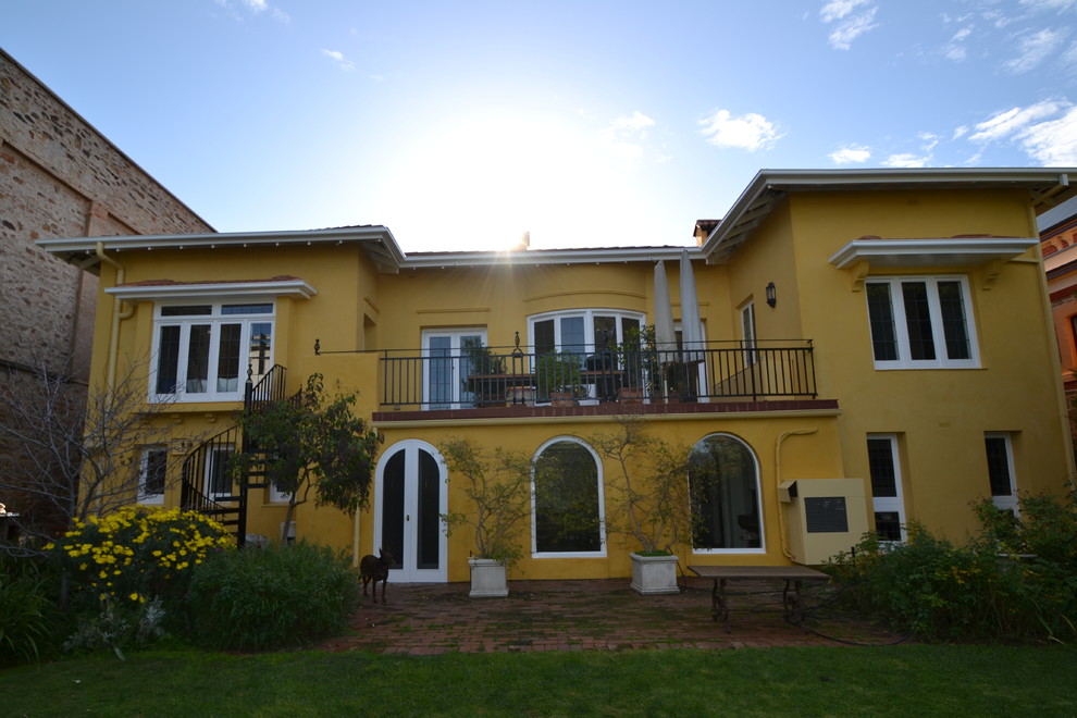 Esempio della facciata di una casa gialla mediterranea a due piani con rivestimento in stucco
