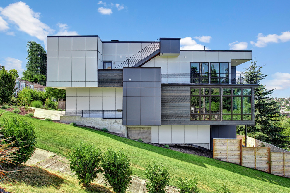 Cette image montre une façade de maison grise design à deux étages et plus avec un toit plat.