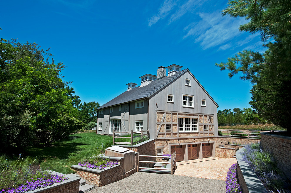 This is an example of a large farmhouse house exterior in New York with three floors, wood cladding and a pitched roof.