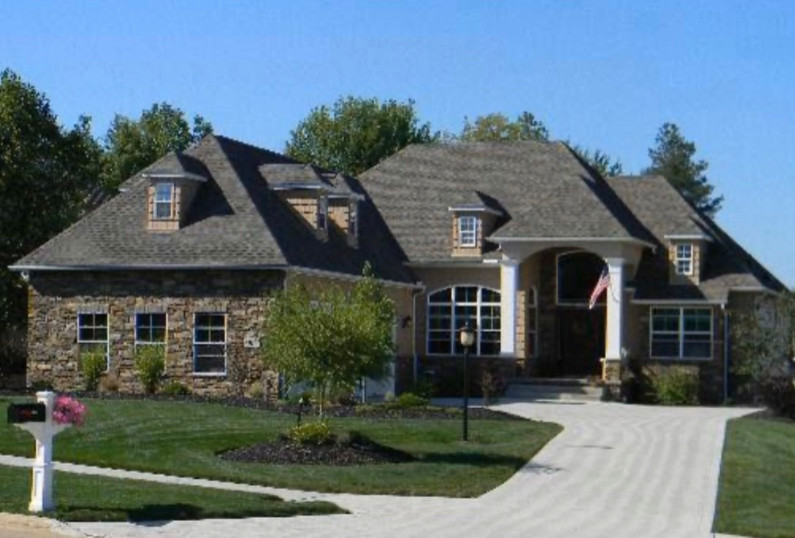 Cette photo montre une façade de maison marron en pierre de taille moyenne et à un étage avec un toit à quatre pans et un toit en shingle.