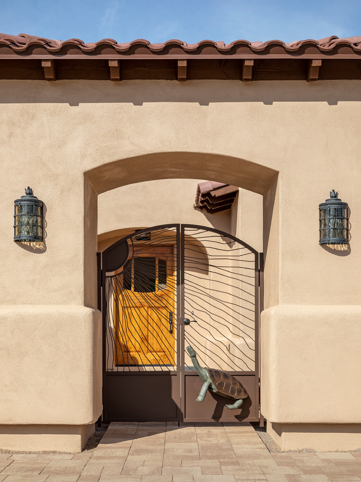 Cette image montre une grande façade de maison beige sud-ouest américain en stuc de plain-pied avec un toit à quatre pans et un toit en tuile.