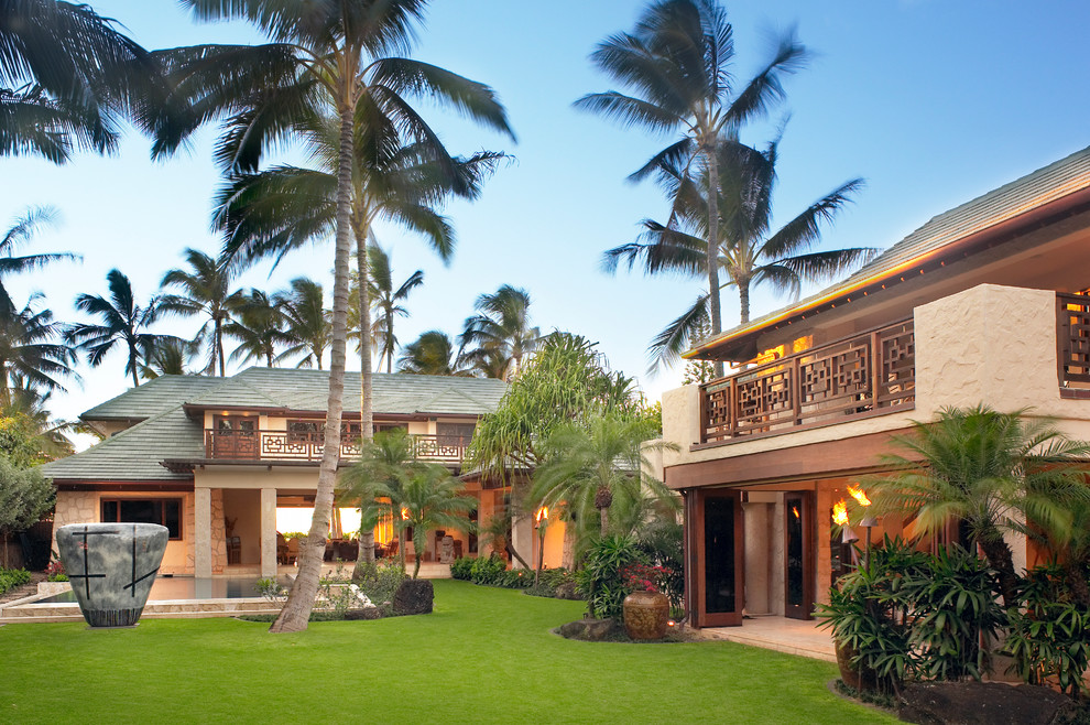 Bild på ett stort tropiskt beige hus, med två våningar och stuckatur