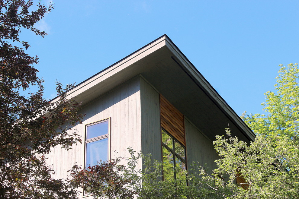 Modelo de fachada de casa gris actual de tamaño medio de dos plantas con revestimiento de madera