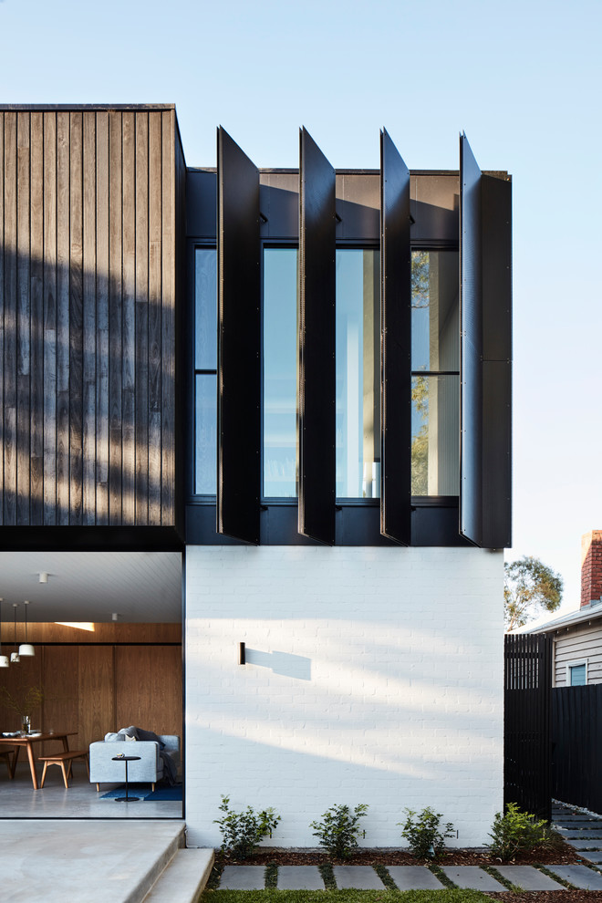 Modelo de fachada de casa negra actual grande de dos plantas con revestimiento de madera, tejado plano y tejado de metal