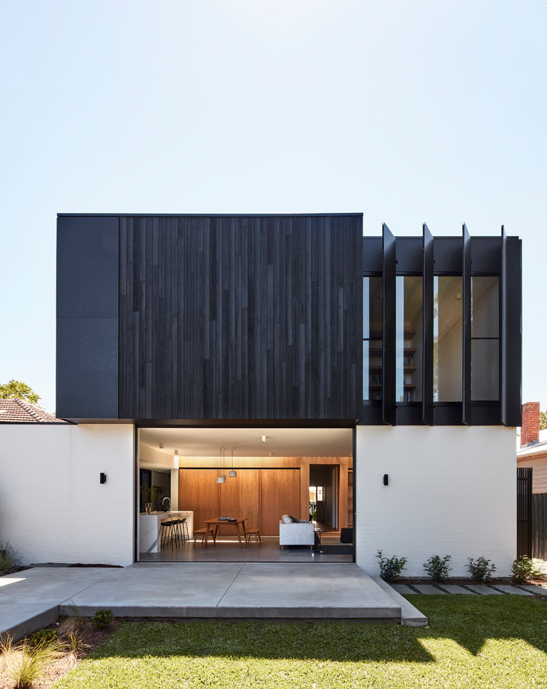 Modelo de fachada de casa negra contemporánea grande de dos plantas con revestimiento de madera, tejado plano y tejado de metal