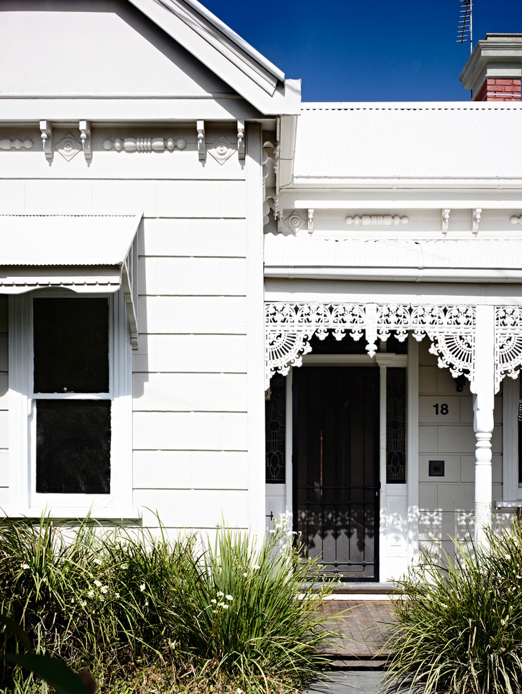 Design ideas for a white and small victorian bungalow house exterior in Melbourne with wood cladding and a pitched roof.