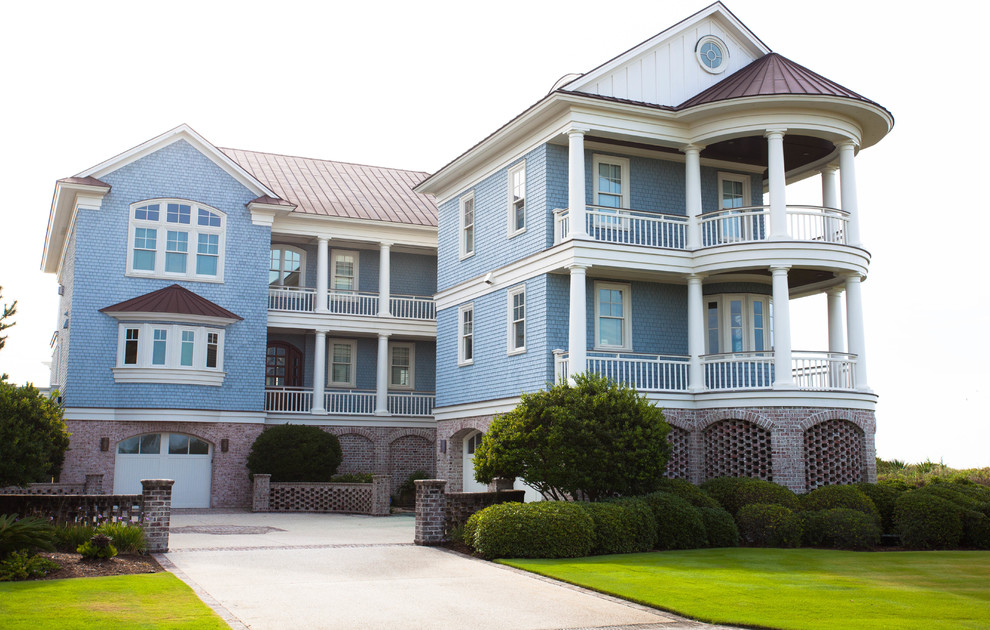 Immagine della villa ampia blu classica a tre piani con rivestimento in legno, tetto a padiglione e copertura in metallo o lamiera