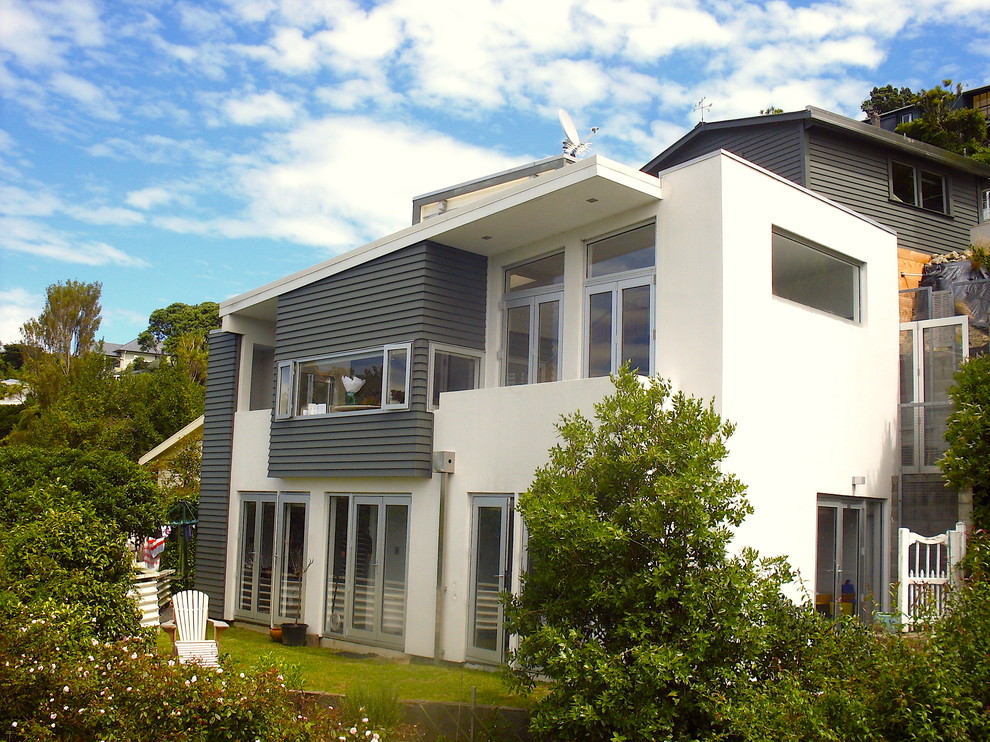Small and gey contemporary house exterior in Wellington with three floors and wood cladding.