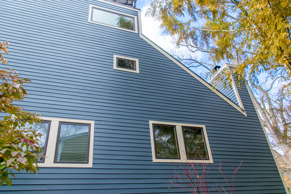 Diseño de fachada de casa azul contemporánea grande de tres plantas con revestimiento de aglomerado de cemento
