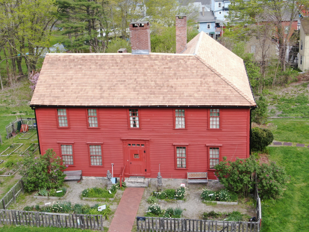 Cette image montre une grande façade de maison rouge rustique en bois à un étage avec un toit à deux pans et un toit en shingle.