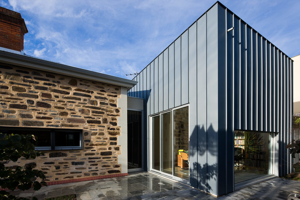 Cette photo montre une façade de maison métallique et grise tendance de taille moyenne et de plain-pied avec un toit plat.