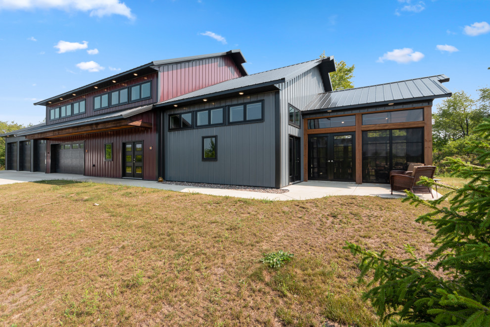 На фото: большой, двухэтажный, разноцветный частный загородный дом в стиле лофт с облицовкой из металла, двускатной крышей и металлической крышей с