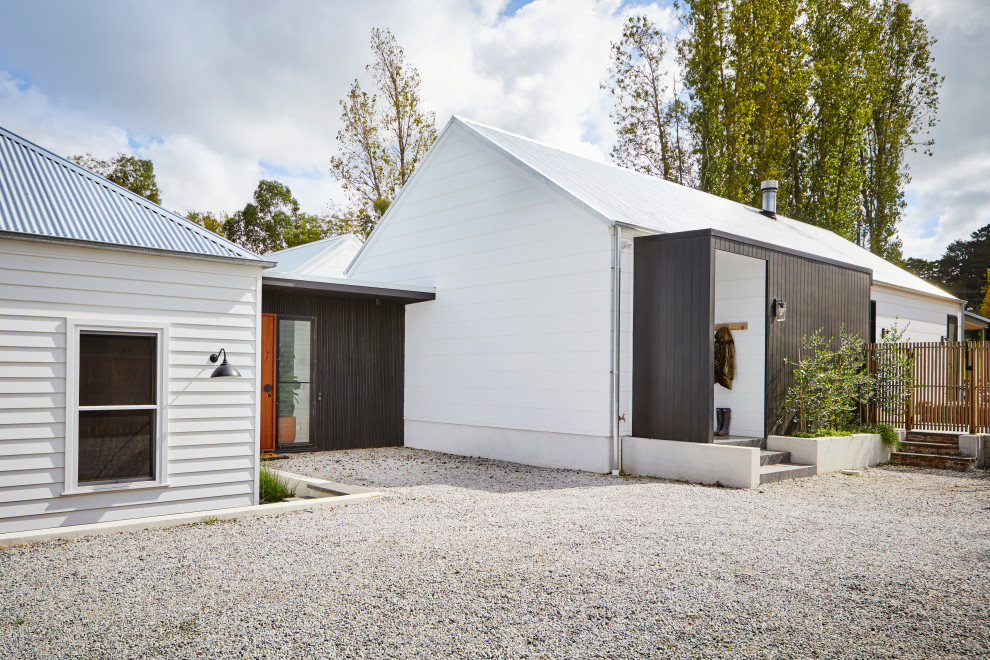 Imagen de fachada de casa blanca minimalista grande de una planta con revestimiento de madera, tejado a cuatro aguas y tejado de metal