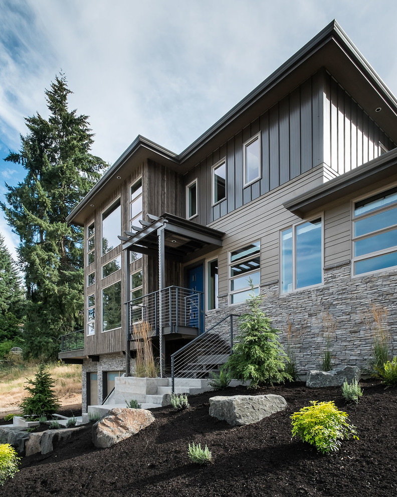 Large and brown contemporary house exterior in Portland with wood cladding, three floors and a hip roof.