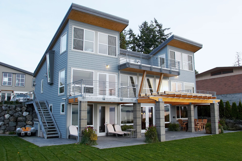 Mid-sized modern gray three-story concrete fiberboard house exterior idea in Seattle with a shed roof and a metal roof