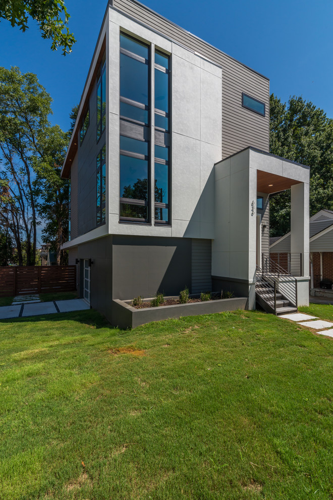 Imagen de fachada de casa gris moderna de tamaño medio de tres plantas con revestimientos combinados, tejado plano y tablilla