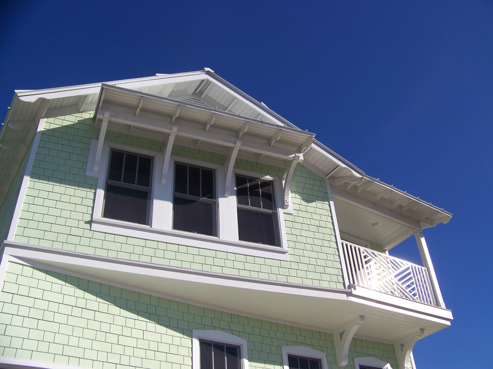 На фото: трехэтажный, зеленый дом в морском стиле с комбинированной облицовкой с