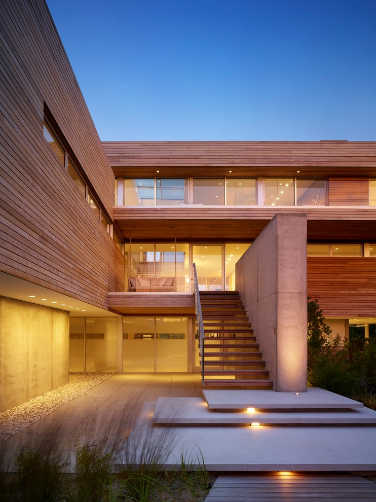 Ispirazione per la facciata di una casa contemporanea a tre piani con rivestimento in legno, tetto piano e terreno in pendenza