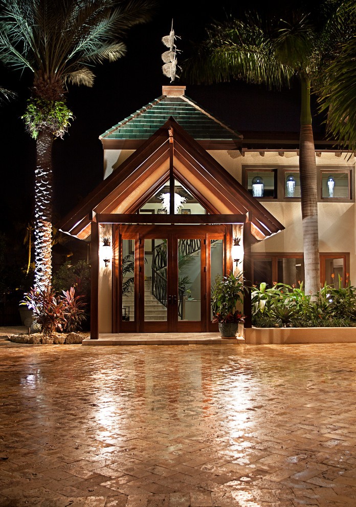 Modelo de fachada beige tropical grande de tres plantas con revestimiento de estuco