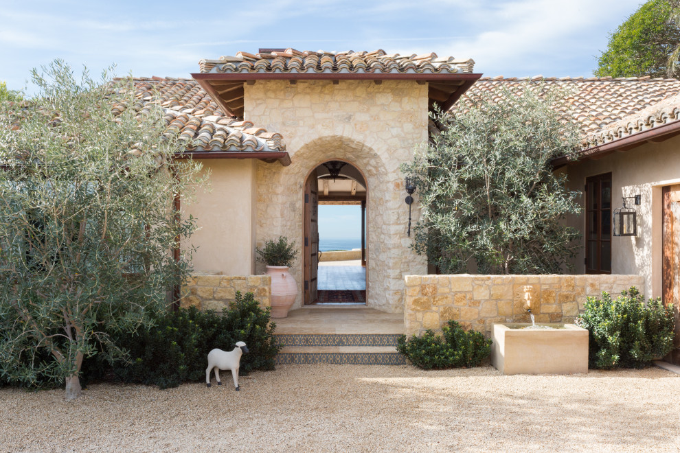 Imagen de fachada de casa beige mediterránea de tamaño medio de una planta con revestimiento de piedra, tejado a cuatro aguas y tejado de teja de barro