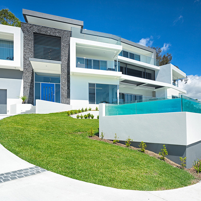 Foto della villa grande bianca contemporanea a tre piani con rivestimento in stucco, tetto piano e copertura in metallo o lamiera