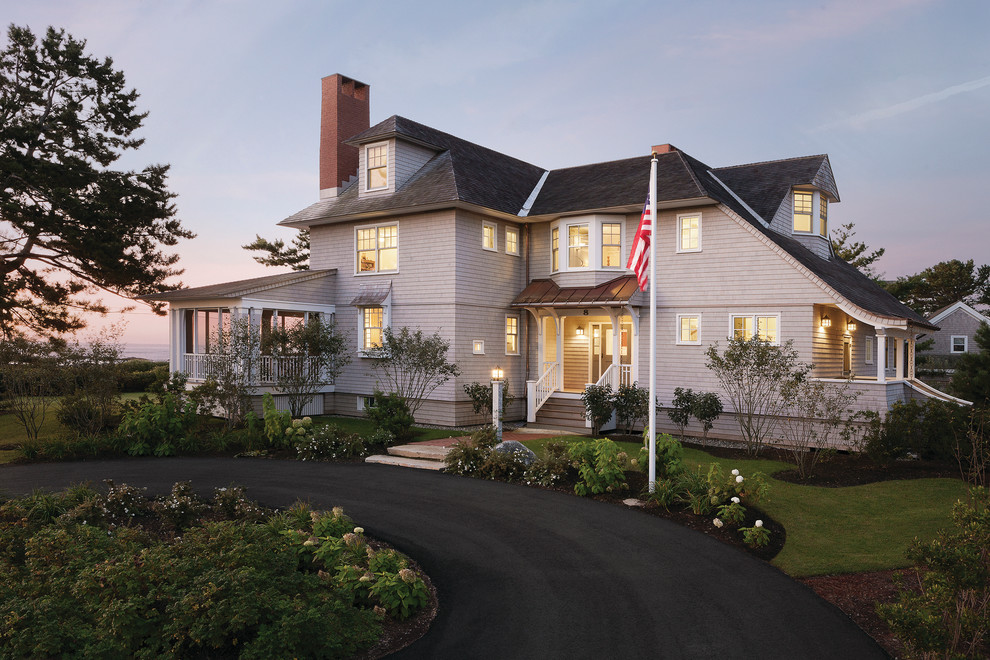 На фото: большой, трехэтажный, деревянный, серый дом в морском стиле с двускатной крышей с