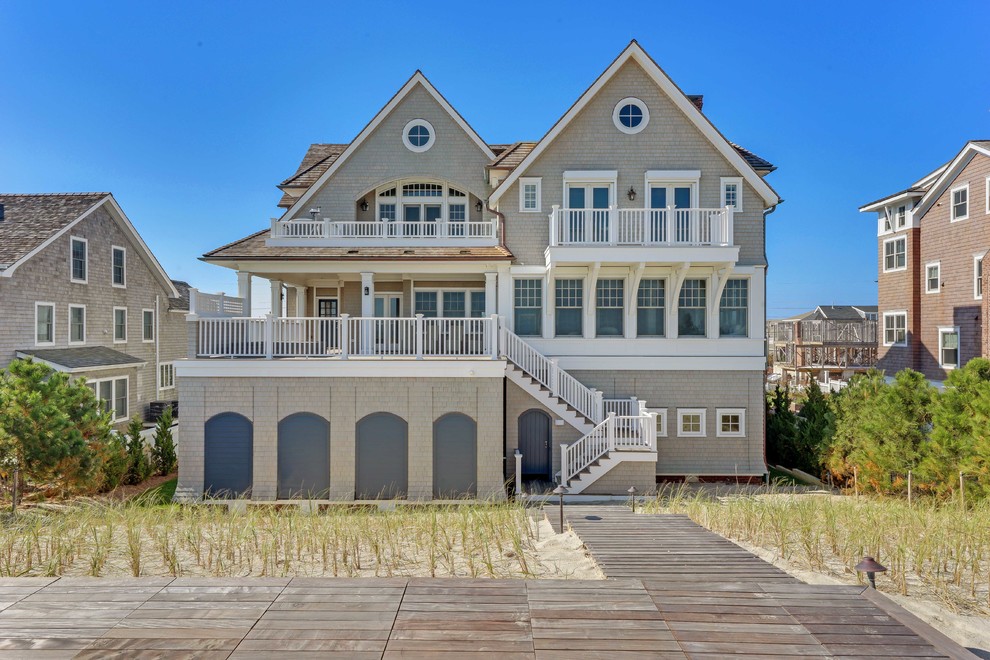 Example of a huge beach style beige three-story wood exterior home design in New York with a shingle roof