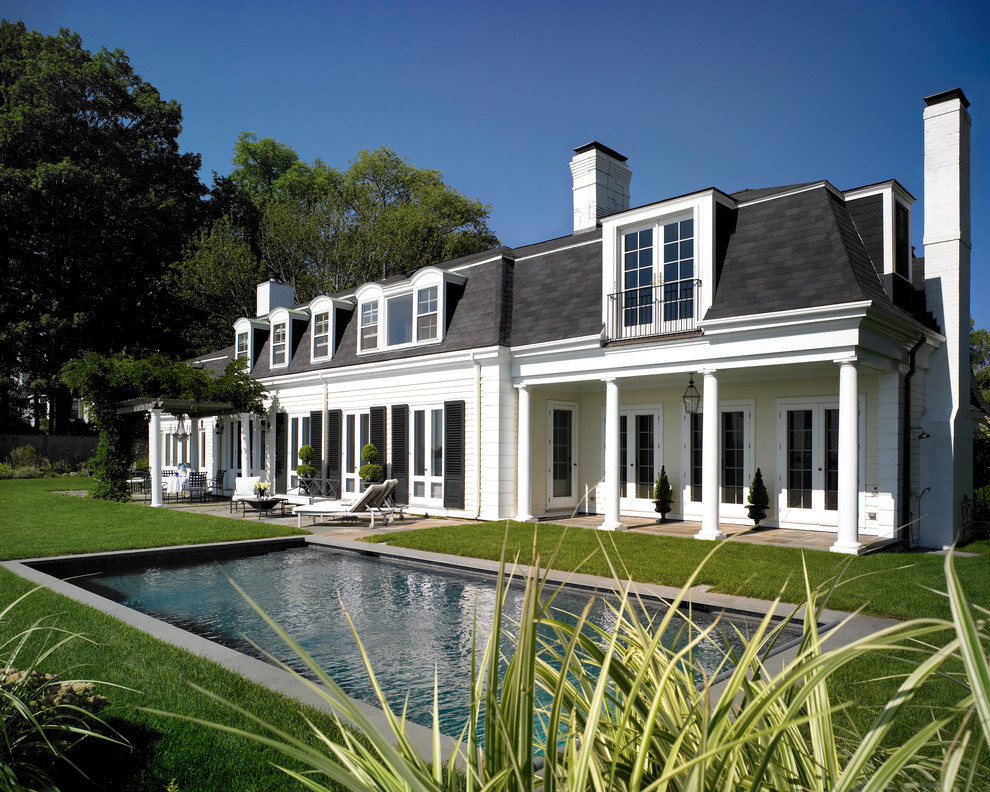 Diseño de fachada blanca tradicional de tamaño medio de dos plantas con revestimiento de madera y tejado a cuatro aguas