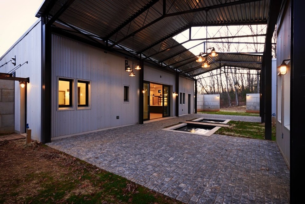 Esempio della facciata di una casa piccola grigia contemporanea a un piano con rivestimento in metallo e copertura in metallo o lamiera
