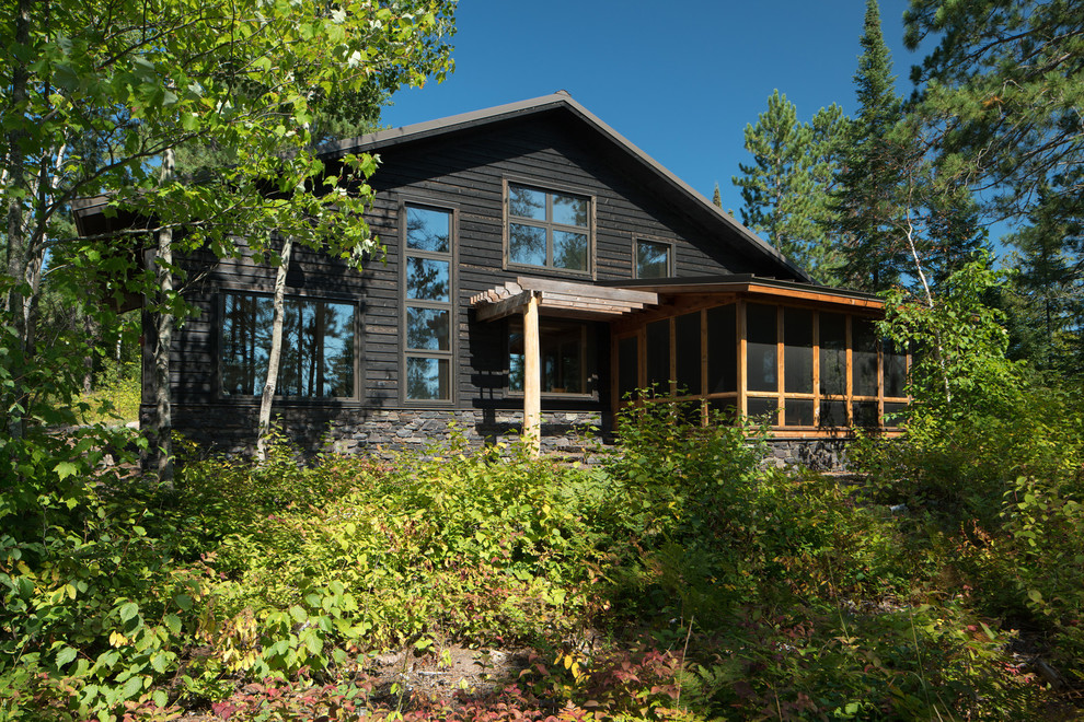Cette image montre une façade de maison noire nordique en bois de taille moyenne et à un étage avec un toit à deux pans.