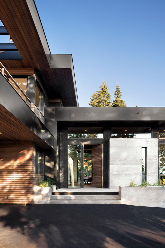 Cette image montre une grande façade de maison grise minimaliste à un étage avec un revêtement mixte et un toit plat.