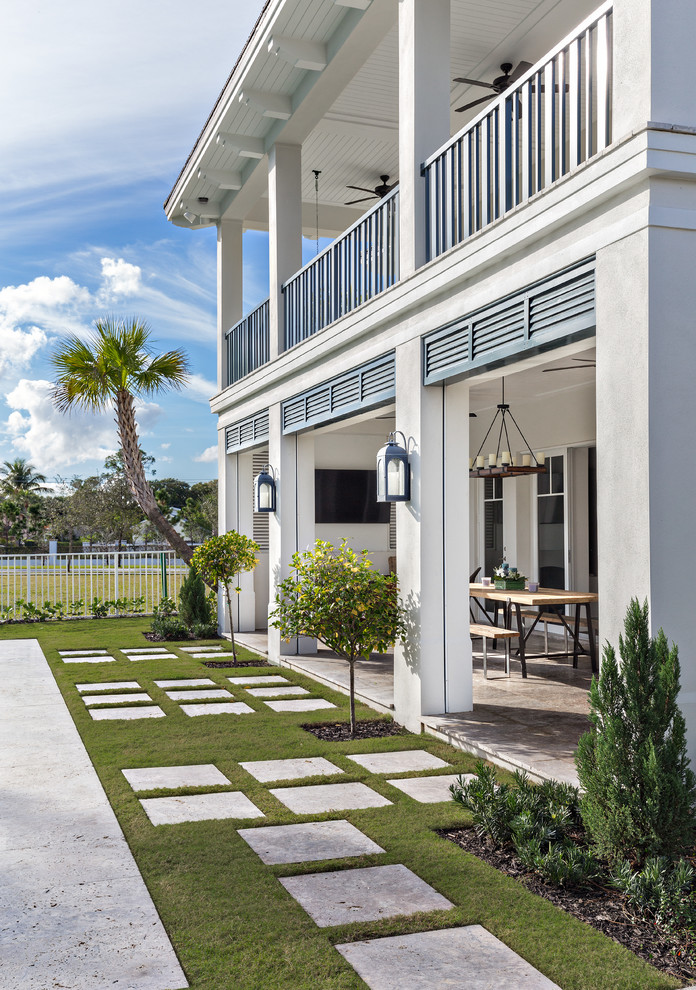 Diseño de fachada blanca costera de tamaño medio de dos plantas con revestimiento de estuco y tejado a cuatro aguas
