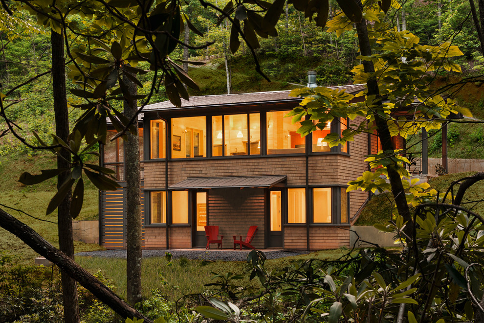 Cette photo montre une petite façade de maison marron montagne en bois à un étage avec un toit à deux pans et un toit en métal.