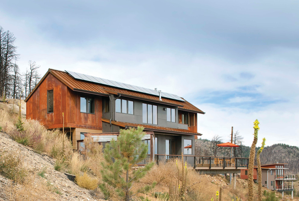 Réalisation d'une façade de maison grise chalet à un étage avec un revêtement mixte, un toit à deux pans et un toit en métal.