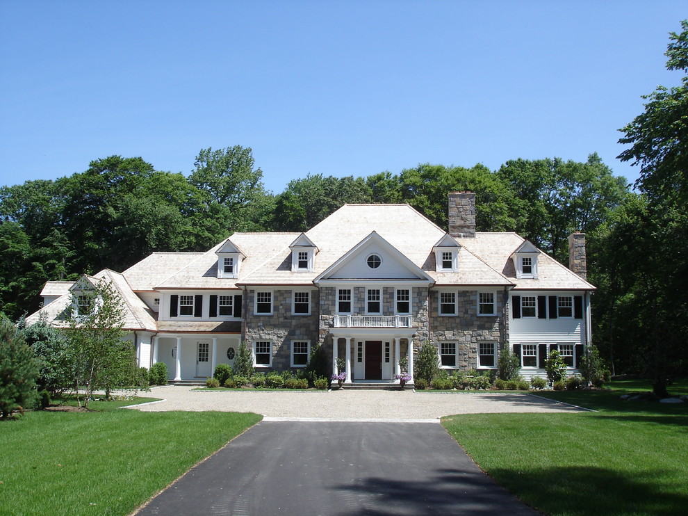 Exemple d'une grande façade de maison multicolore chic en pierre à un étage avec un toit à quatre pans et un toit en shingle.