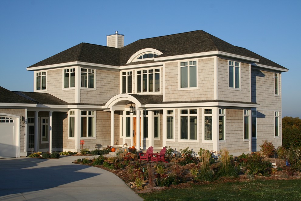Inspiration for a beige traditional two floor house exterior in Other with wood cladding.