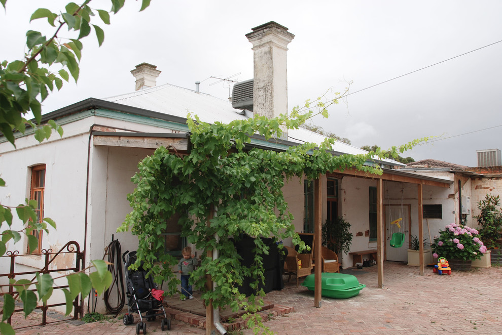 Diseño de fachada de casa beige rural grande de una planta con revestimiento de estuco, tejado a dos aguas y tejado de metal