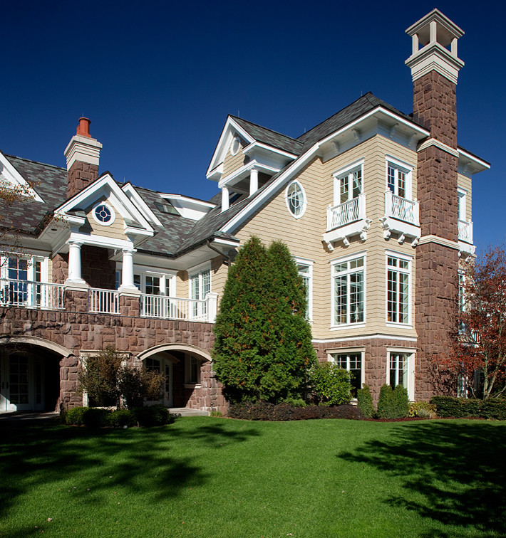 Cette image montre une très grande façade de maison beige traditionnelle en bois à deux étages et plus avec un toit à deux pans.