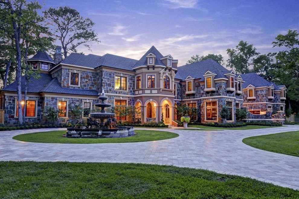 Large elegant gray two-story stone exterior home photo in Houston with a hip roof