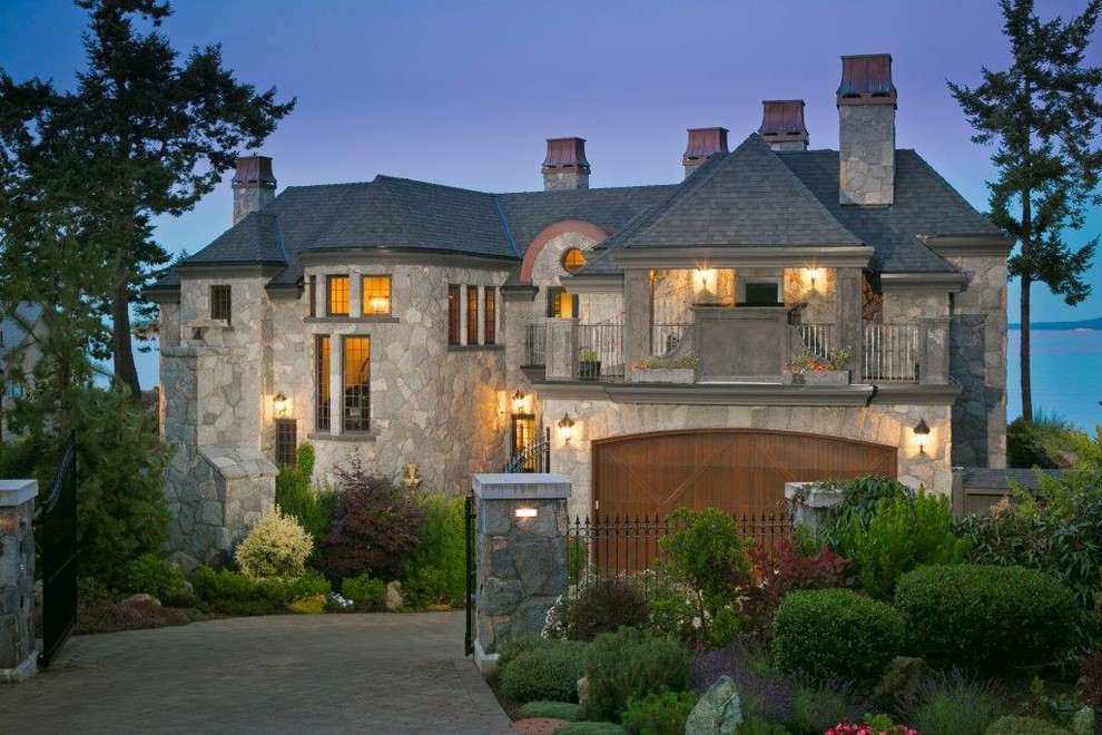 Стильный дизайн: огромный, двухэтажный, серый дом в викторианском стиле с облицовкой из камня и двускатной крышей - последний тренд