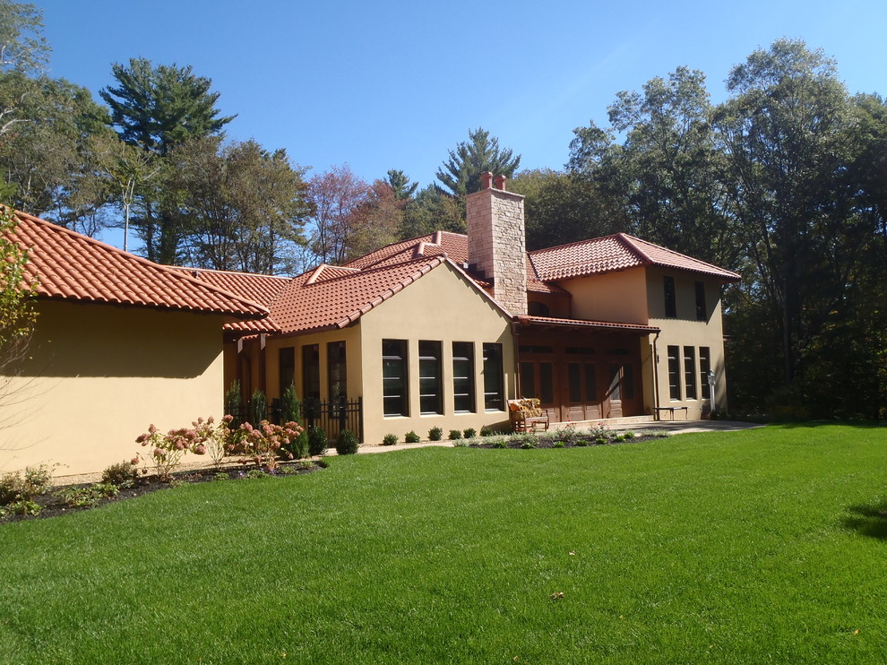 Inspiration for a mediterranean beige three-story exterior home remodel in Boston with a hip roof and a tile roof