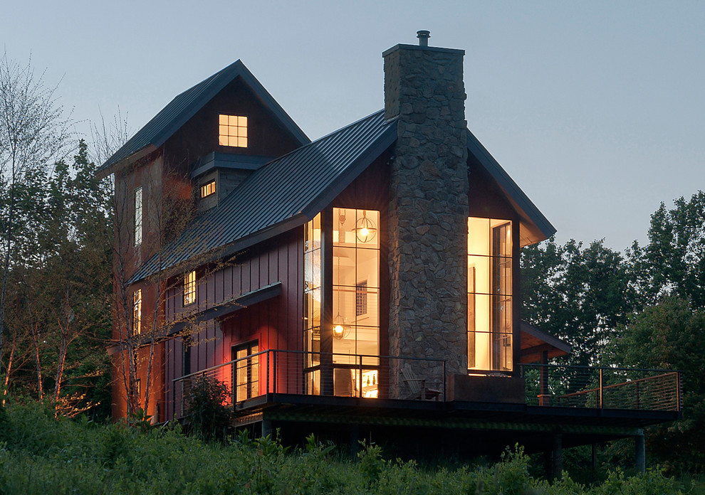 Cette photo montre une façade de maison rouge tendance à deux étages et plus avec un revêtement mixte, un toit à quatre pans et un toit en métal.