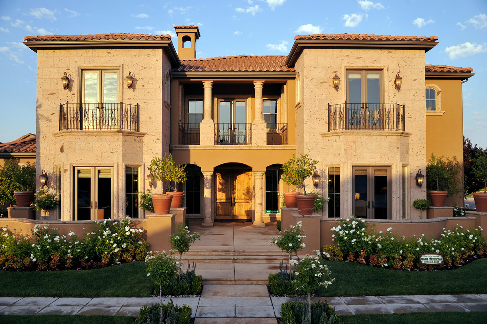 Imagen de fachada de casa beige mediterránea grande de dos plantas con revestimientos combinados, tejado a cuatro aguas y tejado de teja de barro