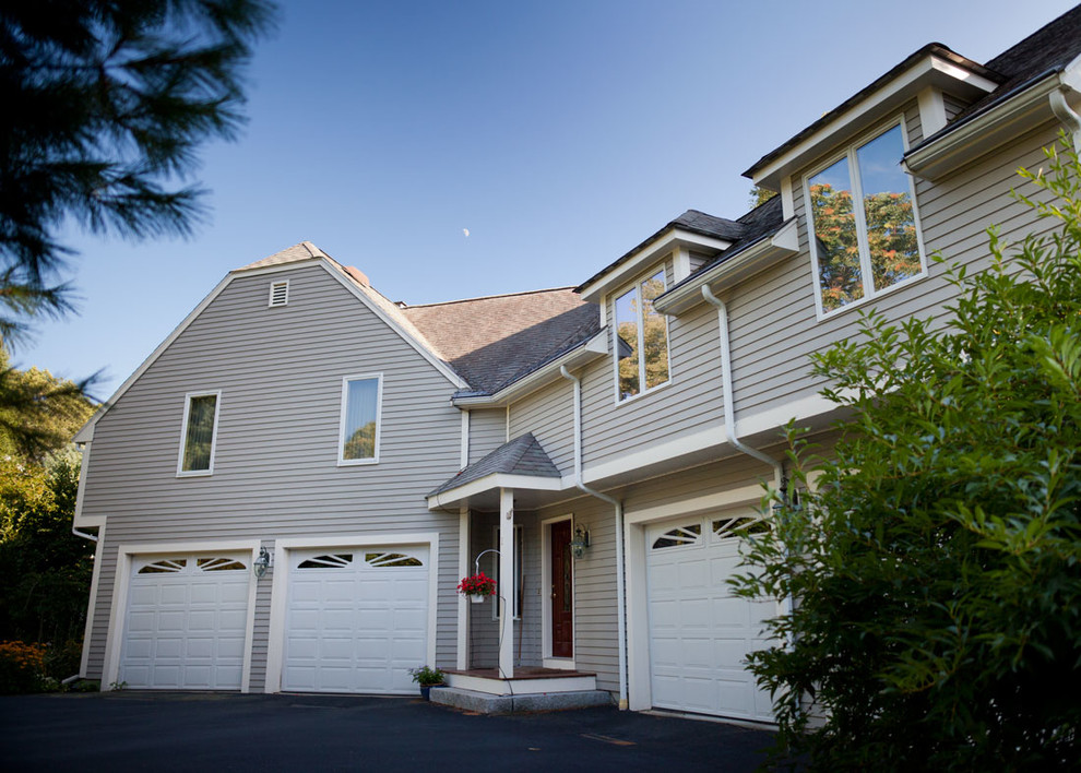 Cette image montre une façade de maison beige design de taille moyenne et à un étage avec un revêtement en vinyle et un toit à quatre pans.