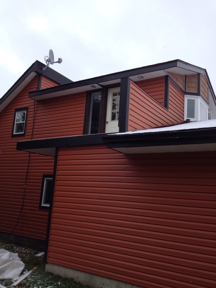 На фото: двухэтажный, оранжевый частный загородный дом в стиле кантри с облицовкой из винила, двускатной крышей и крышей из гибкой черепицы