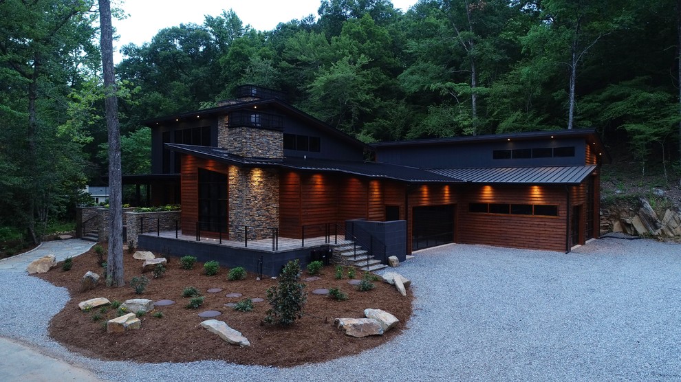На фото: одноэтажный, деревянный, коричневый частный загородный дом среднего размера в стиле рустика с двускатной крышей и металлической крышей с