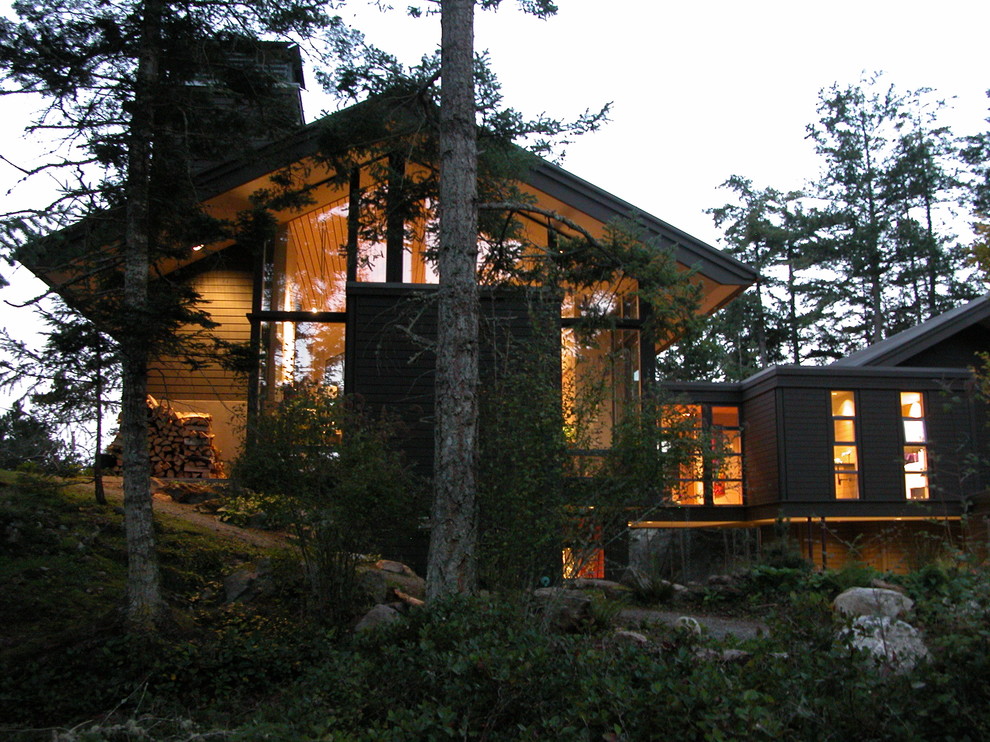 Immagine della facciata di una casa contemporanea con rivestimento in legno e terreno in pendenza