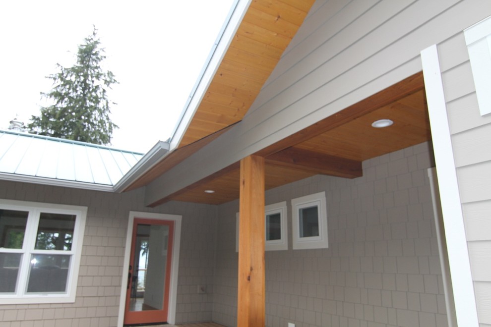 Esempio della facciata di una casa piccola beige american style a un piano con rivestimento in cemento e tetto a capanna